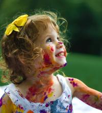 A girl smiling while covered in paint.
