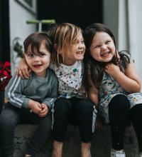 Three kids happily arm-in-arm.