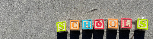 Letter blocks spelling out 'schools' in the sand.